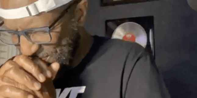 Man praying with hands clasped in studio.